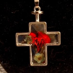 Glass 3D cross necklace with dried flowers inside.